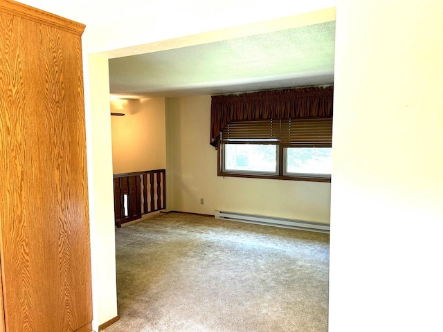 carpeted empty room with a baseboard heating unit and baseboards