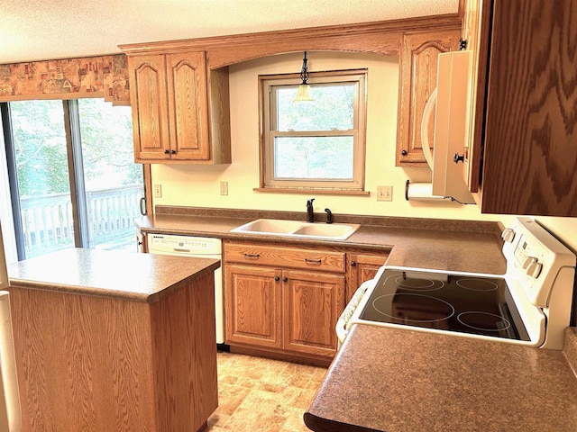 kitchen featuring a textured ceiling, white appliances, a healthy amount of sunlight, and a sink