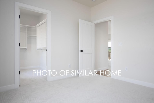 unfurnished bedroom featuring a walk in closet, baseboards, a closet, and carpet flooring