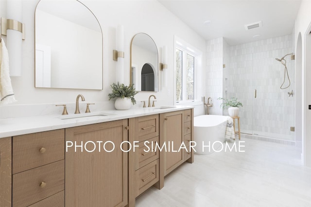 full bathroom with double vanity, a freestanding tub, a stall shower, and a sink