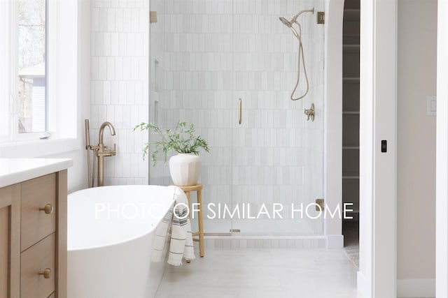 full bath featuring a shower stall, vanity, and a freestanding tub