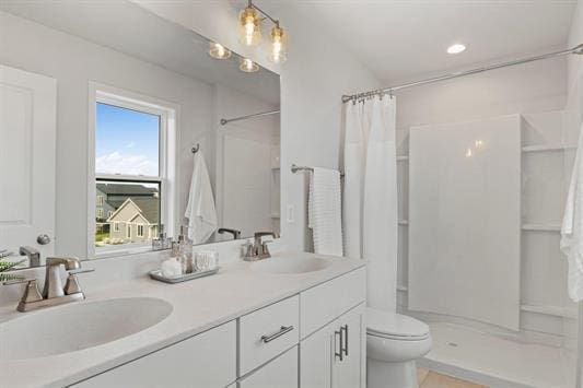 bathroom with a sink, toilet, double vanity, and a shower stall