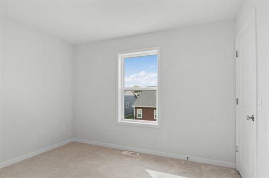 spare room with light carpet, visible vents, and baseboards