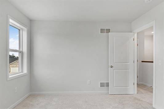 unfurnished room featuring light carpet, visible vents, and baseboards