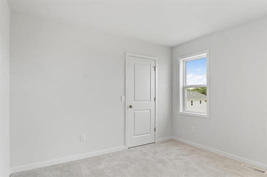 unfurnished room with visible vents, baseboards, and light carpet