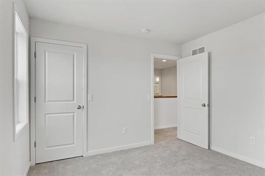 unfurnished bedroom with visible vents, baseboards, and light colored carpet