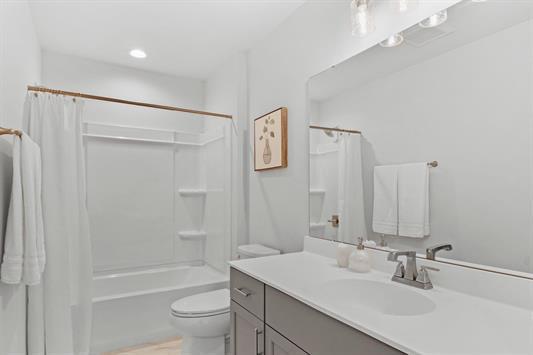 bathroom with vanity, toilet, and shower / bathtub combination with curtain