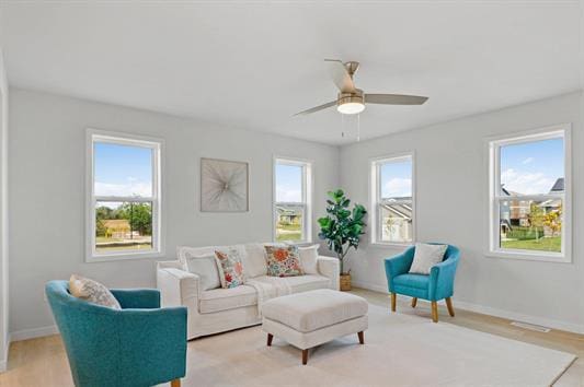 living area featuring light wood-style flooring, baseboards, and ceiling fan