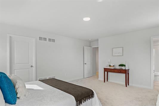 bedroom with visible vents, baseboards, and light carpet