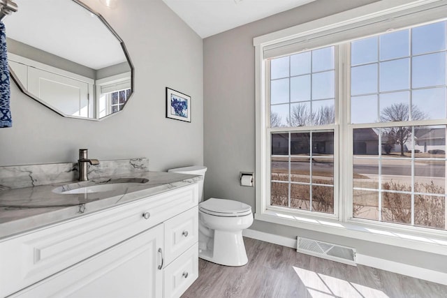 bathroom featuring visible vents, toilet, wood finished floors, baseboards, and vanity