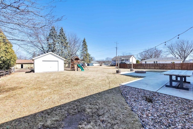 view of yard with a patio, a fenced backyard, a playground, a fire pit, and an outdoor structure