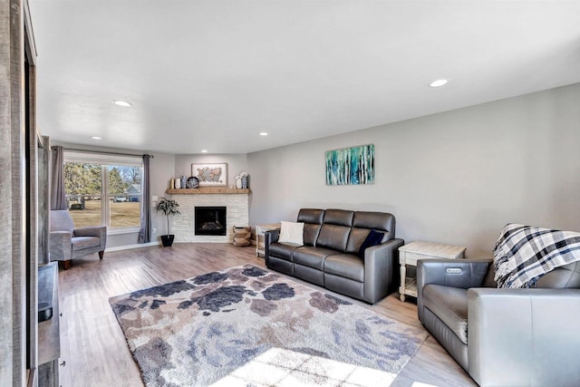 living room with a stone fireplace, recessed lighting, baseboards, and wood finished floors