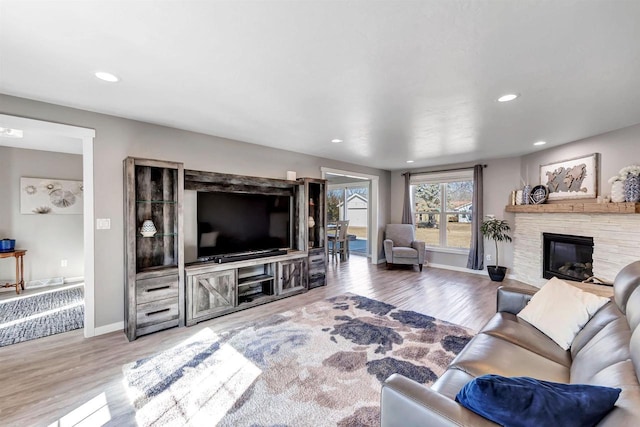 living room featuring recessed lighting, a fireplace, baseboards, and wood finished floors