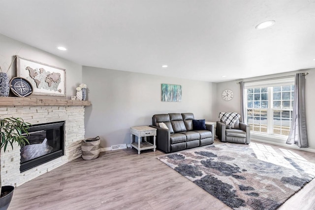 living area featuring visible vents, baseboards, recessed lighting, a fireplace, and wood finished floors