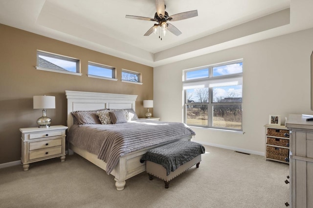 bedroom featuring light carpet, visible vents, baseboards, and a tray ceiling