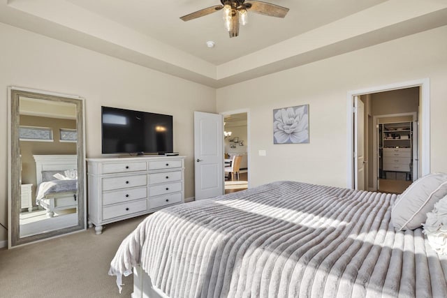 bedroom with a raised ceiling, carpet floors, and ceiling fan