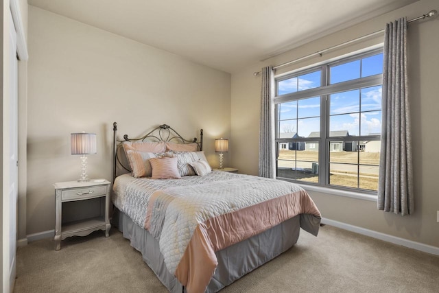 bedroom with multiple windows, light colored carpet, and baseboards