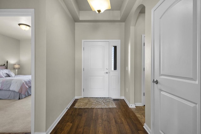 hallway featuring baseboards, arched walkways, and dark wood-style floors