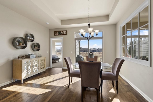 dining room featuring a tray ceiling, baseboards, wood finished floors, and a chandelier