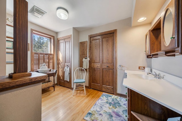 interior space featuring vanity, visible vents, baseboards, and wood-type flooring