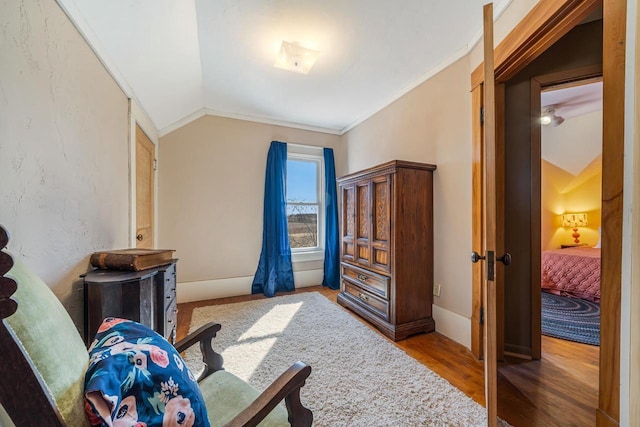 interior space with baseboards, wood finished floors, crown molding, and vaulted ceiling