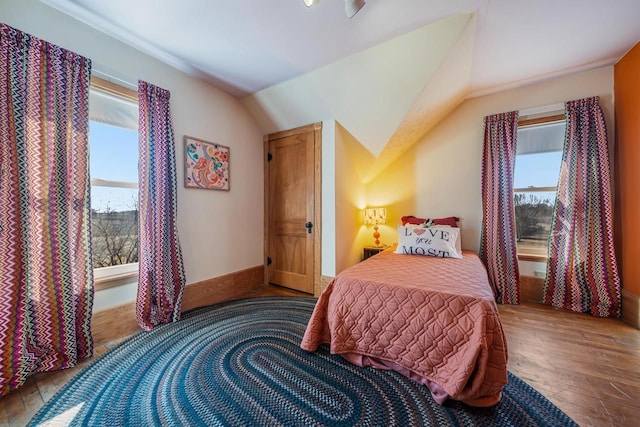 bedroom featuring lofted ceiling, wood finished floors, and baseboards