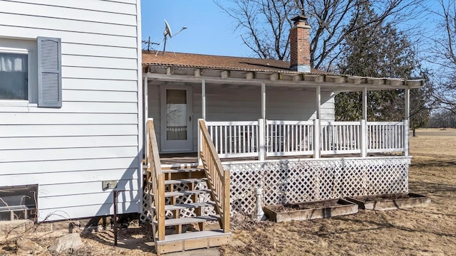 back of house featuring a porch and a chimney