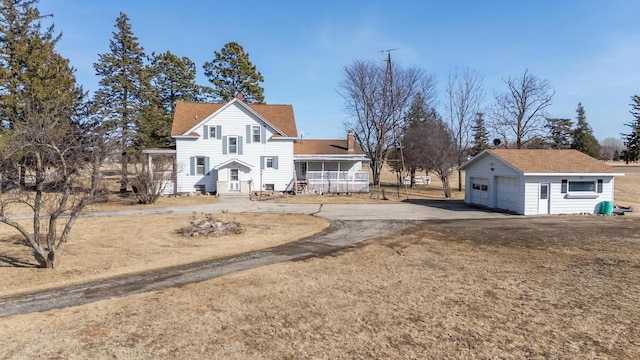 back of house with an outbuilding, a detached garage, and dirt driveway