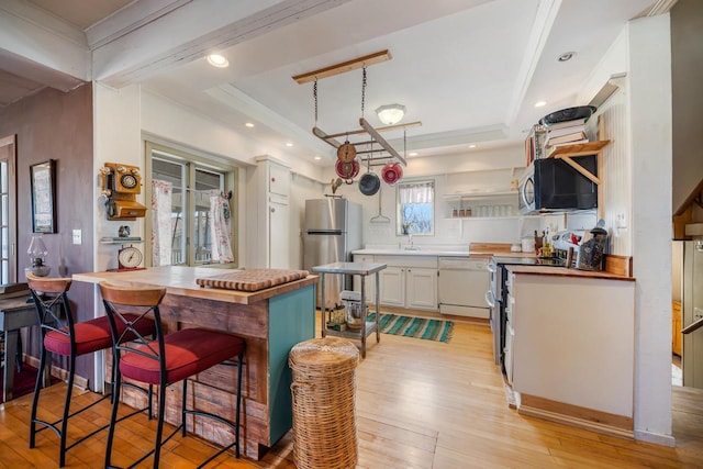 kitchen featuring open shelves, stainless steel appliances, butcher block counters, light wood finished floors, and a raised ceiling