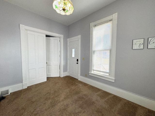 entryway with baseboards, visible vents, and dark colored carpet