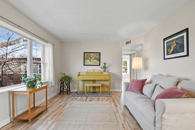 living area with visible vents, baseboards, and wood finished floors