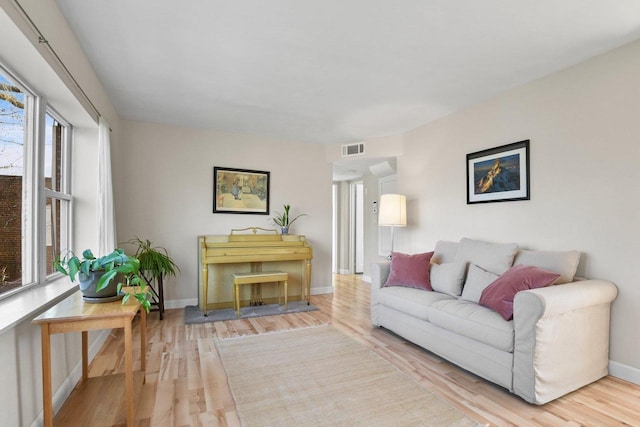 living room with visible vents, baseboards, and wood finished floors