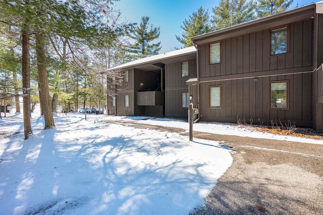 snow covered back of property featuring board and batten siding