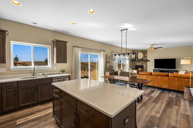 kitchen featuring dark wood-type flooring, a fireplace, light countertops, and a sink