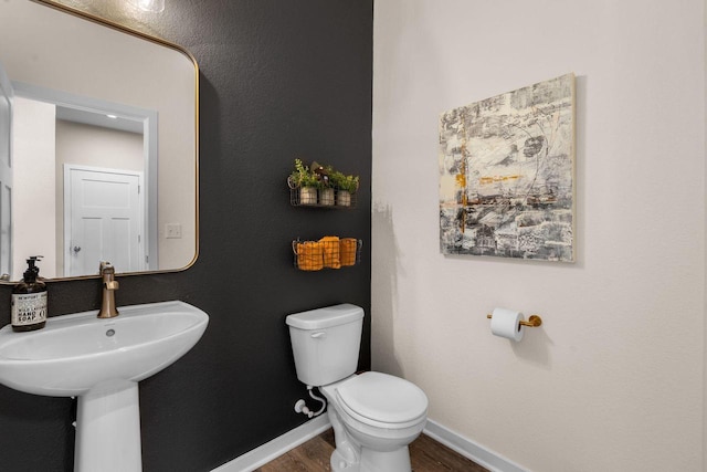 half bath featuring toilet, baseboards, and wood finished floors