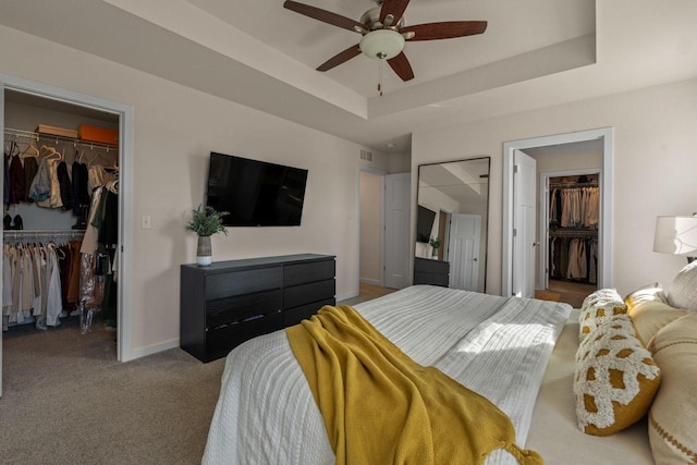 carpeted bedroom featuring a walk in closet, a raised ceiling, and a closet