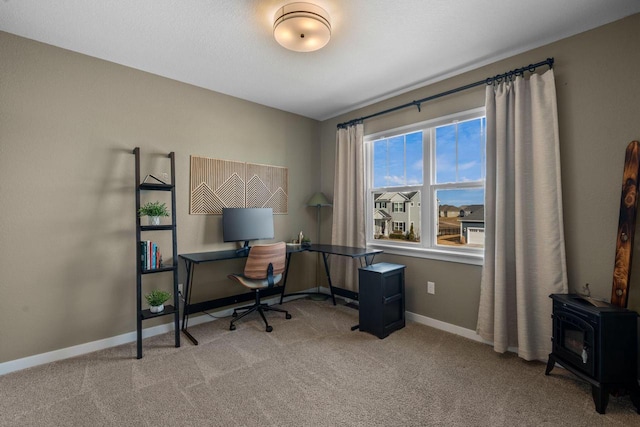 office area featuring a wood stove, carpet, and baseboards