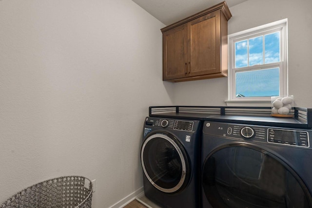 clothes washing area featuring cabinet space, washer and dryer, and baseboards