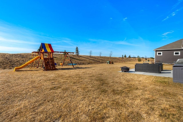 view of yard with an outdoor living space with a fire pit, a playground, and a patio area