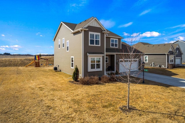 traditional-style home featuring an attached garage, concrete driveway, a playground, and a front lawn