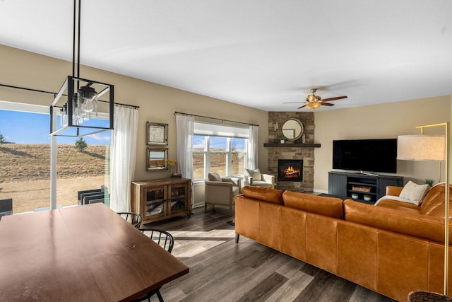 living room with ceiling fan, dark wood-type flooring, and a large fireplace