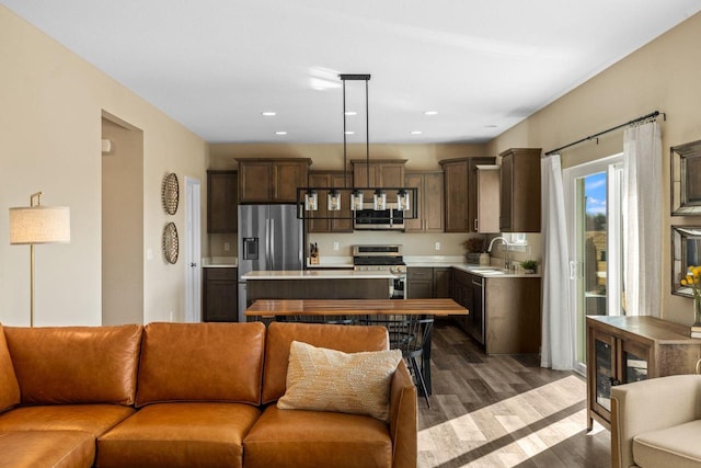 kitchen featuring a sink, open floor plan, stainless steel appliances, light countertops, and dark brown cabinets