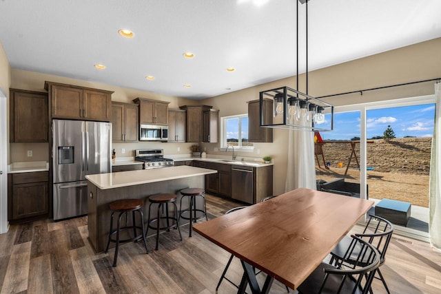 kitchen with a center island, dark brown cabinetry, light countertops, stainless steel appliances, and a sink