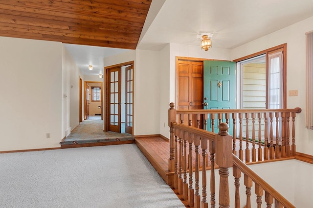 corridor featuring an upstairs landing, baseboards, french doors, and a healthy amount of sunlight