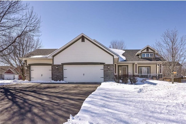 view of front facade featuring a garage, stone siding, roof with shingles, and driveway