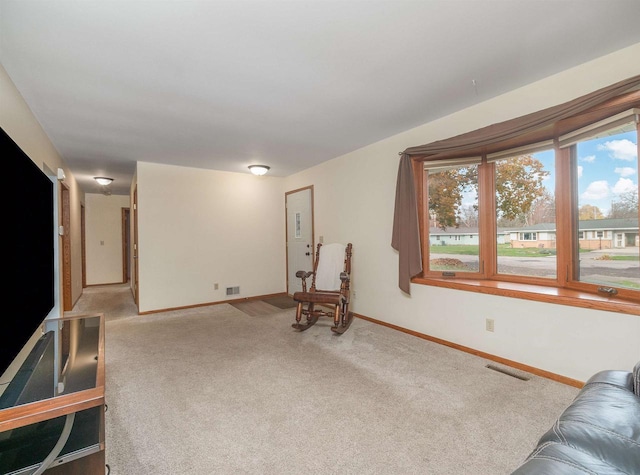 living area featuring light carpet, visible vents, and plenty of natural light