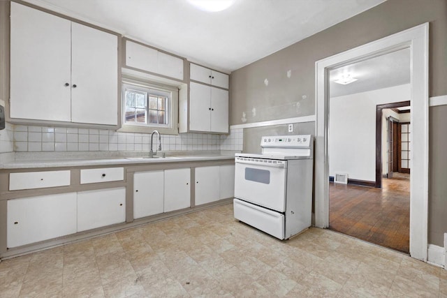 kitchen featuring white range with electric cooktop, white cabinetry, light countertops, and a sink