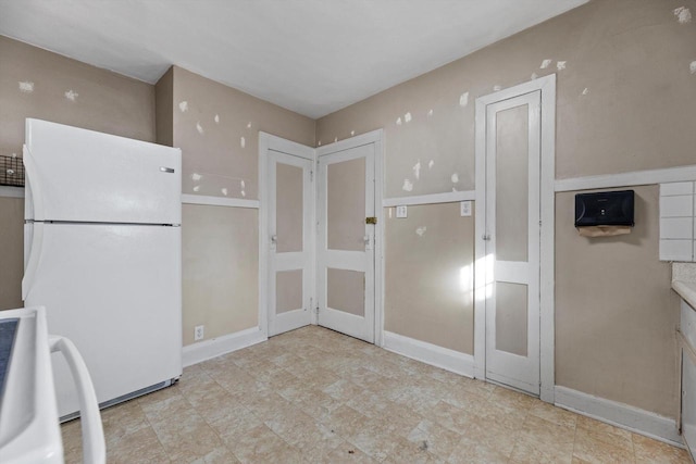 kitchen featuring baseboards, stove, and freestanding refrigerator