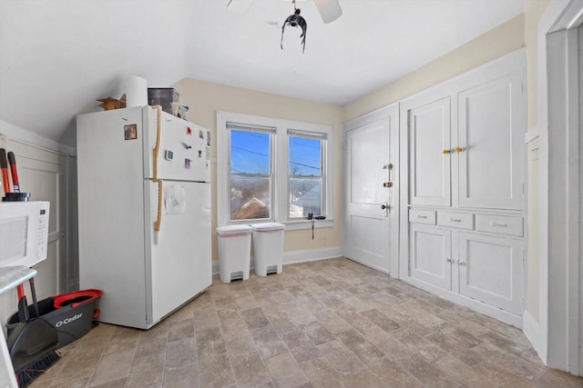 interior space with baseboards, white appliances, lofted ceiling, and white cabinetry