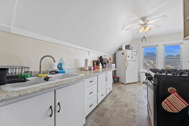 kitchen with a sink, white cabinetry, freestanding refrigerator, black gas range oven, and light countertops